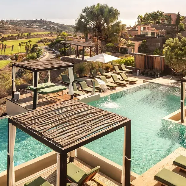 Der luxuriöse Außenpool des Salobre Hotel Resort bietet schattige Liegen und Cabanas mit Blick auf den Golfplatz und die sanften Hügel. Bäume und moderne Unterkünfte umgeben das sonnenbeschienene Pooldeck und sorgen für einen entspannten Aufenthalt im Resort-Stil.