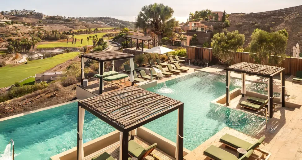 Der luxuriöse Außenpool des Salobre Hotel Resort bietet schattige Liegen und Cabanas mit Blick auf den Golfplatz und die sanften Hügel. Bäume und moderne Unterkünfte umgeben das sonnenbeschienene Pooldeck und sorgen für einen entspannten Aufenthalt im Resort-Stil.